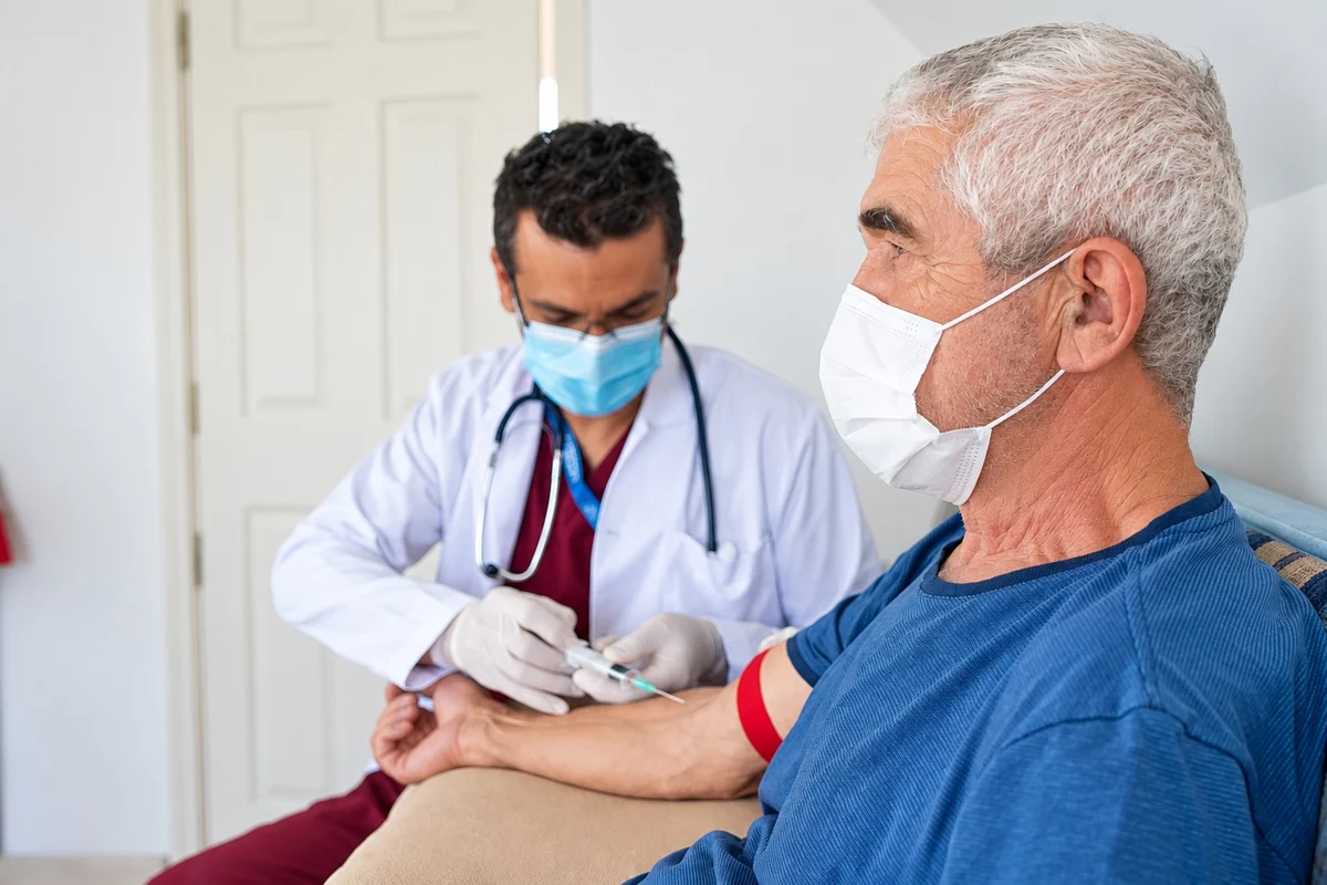 Profissional de saúde realizando coleta de sangue de um paciente em casa